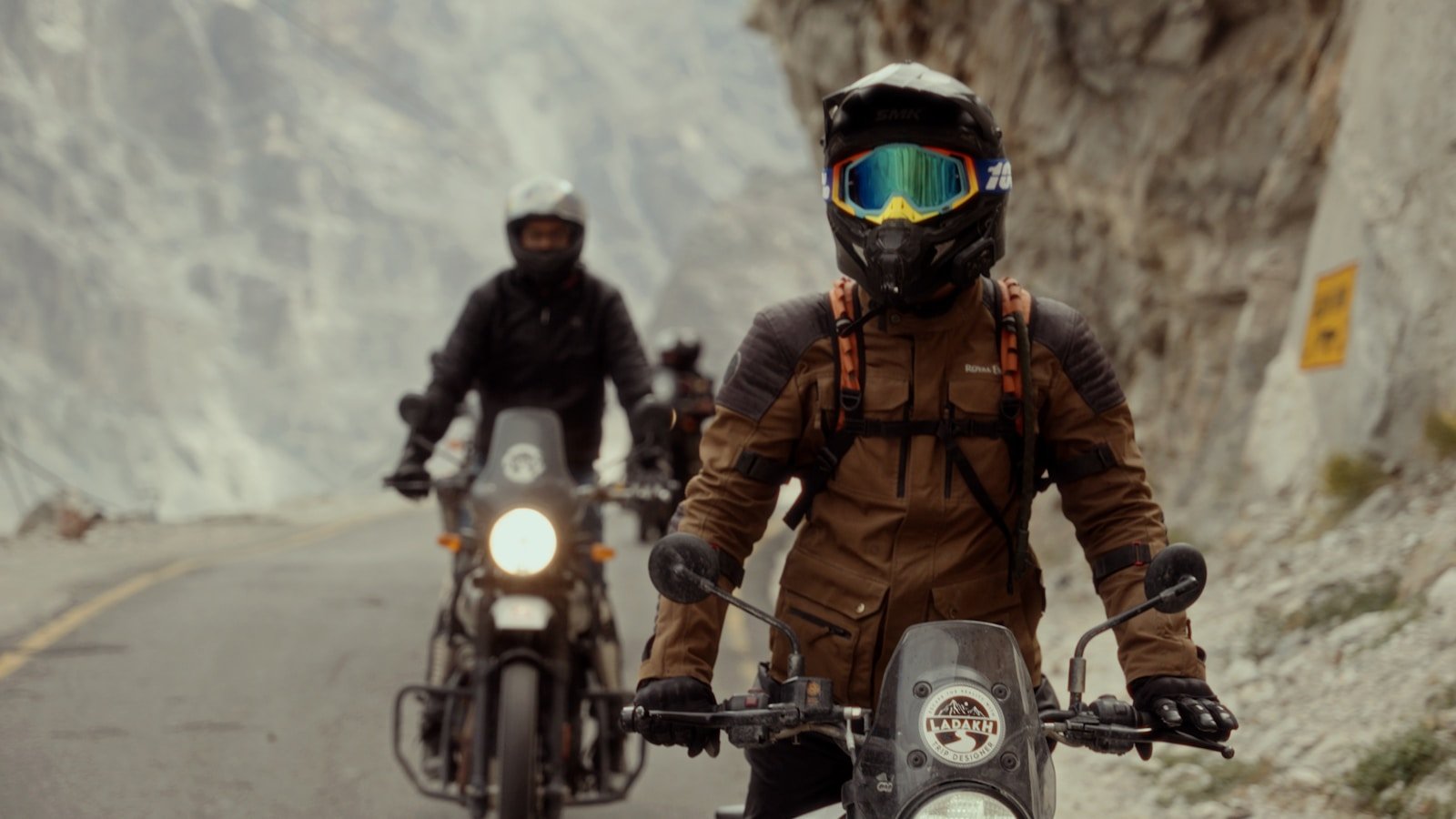 Two people riding motorcycles down a mountain road