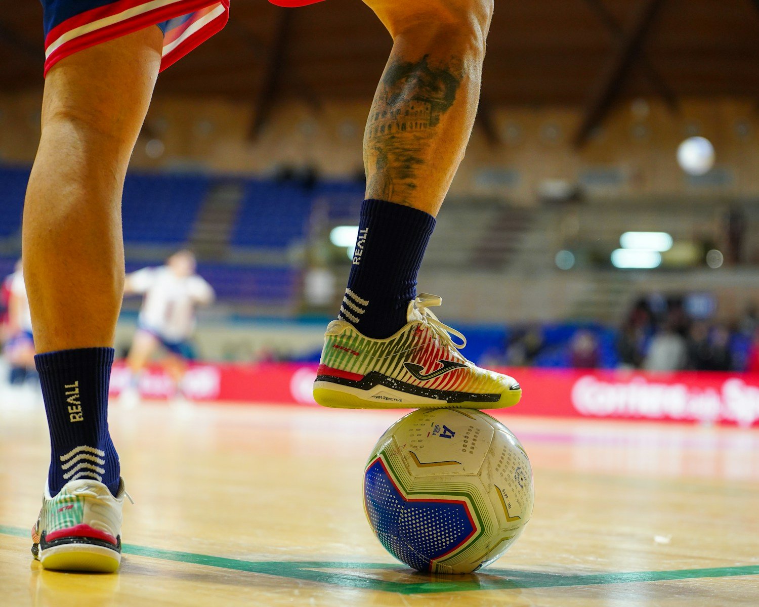 Player with foot on a soccer ball indoors.