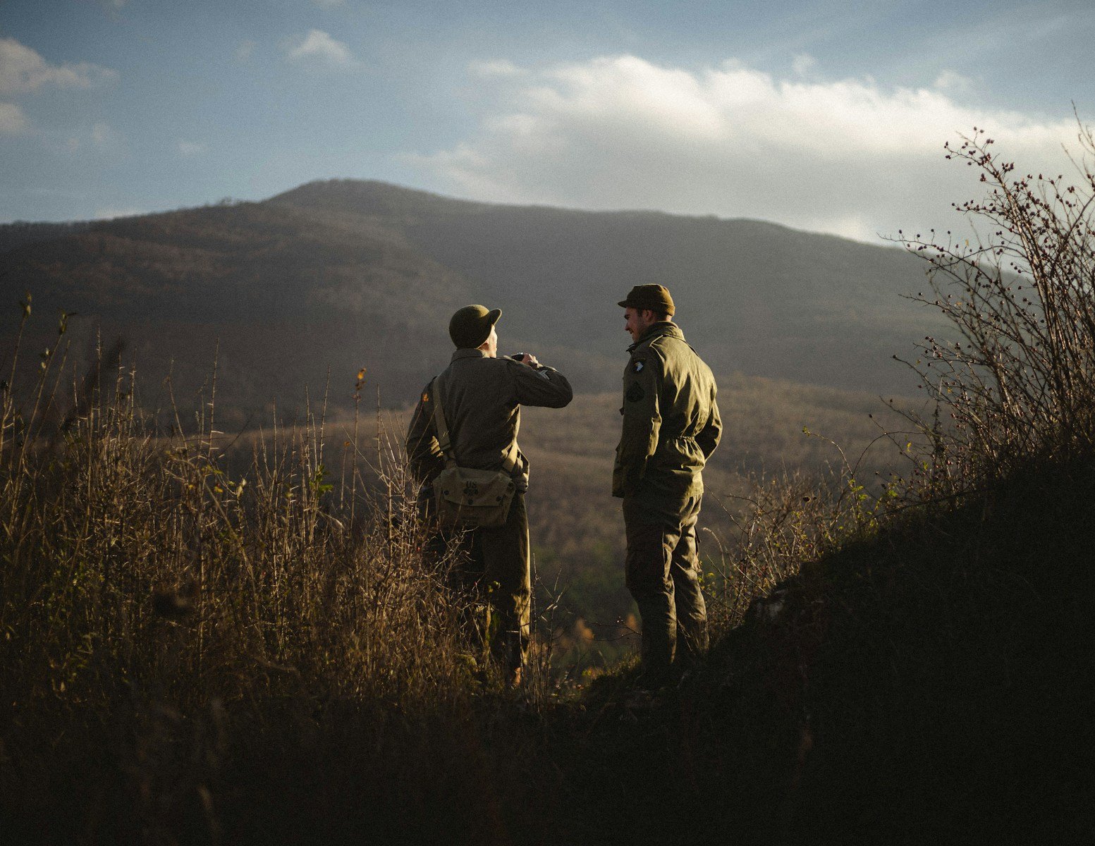 2 men standing on brown grass field during daytime